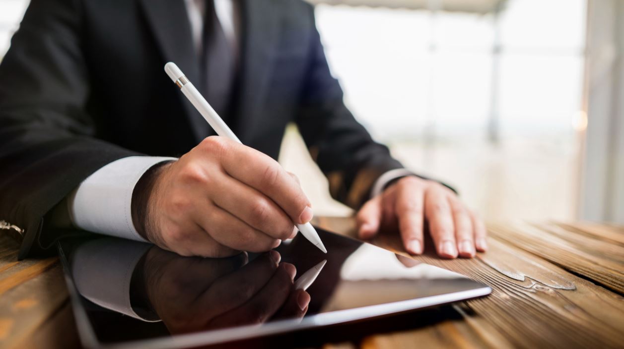 Business owner signing an agreement on a tablet